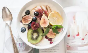Schüssel mit Kokosjoghurt, garniert mit Feigen, Beeren, Kiwi und Zitrone. Ein gesundes Frühstück, das Lust auf mehr macht.