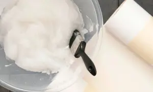 Schüssel mit selbstgemachtem Kleister und Pinsel, dane liegen Tapetenrollen bereit.