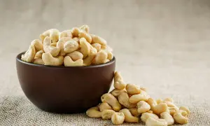 Schale mit Cashewkernen, die zeigen, wie gesund Cashewkerne sind. Ein paar Kerne sind daneben verstreut.