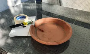Zerbrochener Tontopf, Kleber und Klebeband liegen bereit, um den Schaden zu beheben.