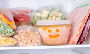 Gefrierbrand vermeiden: Gefrorenes Gemüse und Obst in Beuteln und einem Behälter mit Smiley-Gesicht im Gefrierschrank.
