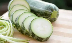 Frische Zucchini, roh essen als Spiralen oder Scheiben auf einem Holzbrett.