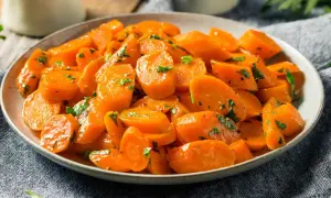 Schüssel mit glasierten, bunte Karotten, garniert mit Petersilie. Ein köstliches Gericht, das Farbe auf den Tisch bringt.