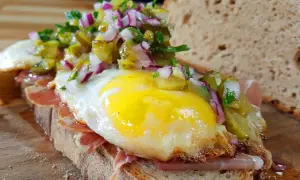 Ein **strammer Max vegetarisch** mit Spiegelei, Schinken, Gewürzgurken und Zwiebeln auf rustikalem Brot.