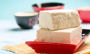 Zwei Blöcke Tofu auf einem roten Teller, bereit zum Genuss. Ja, man kann Tofu roh essen, er ist vielseitig!