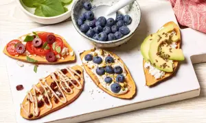 Brotalternativen: Süßkartoffelscheiben belegt mit Tomaten, Feta, Oliven, Blaubeeren, Pistazien, Avocado und Leinsamen.