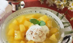 Schüssel mit Apfel-Birnen-Kompott, garniert mit Sahne und Minze. Ein süßer Genuss!