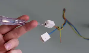 Mit einem Spannungsprüfer wird die Verkabelung für das Anbringen einer Lampe vorbereitet.