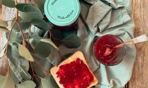 Glas mit Johannisbeermarmelade ohne Gelierzucker, daneben ein Toast mit Marmelade und ein Löffel.