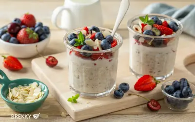Zwei Gläser mit über Nacht eingeweichten Haferflocken, garniert mit frischen Beeren und Mandelsplittern. Ein gesunder Start in den Tag.
