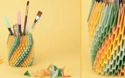 Bunter Stiftehalter aus Origami-Modulen, inspiriert von Papier Ideen. Daneben liegen bunte Papierbögen und kleine Origami-Figuren.