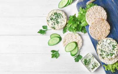 Reiswaffeln mit Frischkäse und Kräutern, Gurkenscheiben und Salat – eine leichte Mahlzeit, die zeigt, welche Reiswaffeln unbedenklich sind.