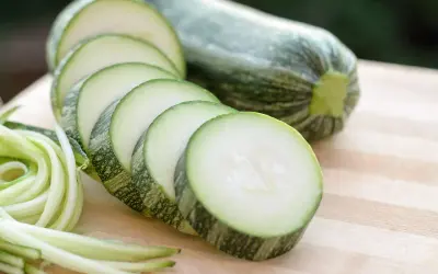 Frische Zucchini, roh essen als Spiralen oder Scheiben auf einem Holzbrett.