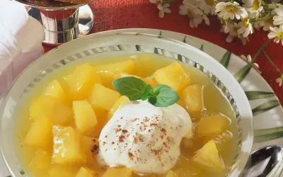 Schüssel mit Apfel-Birnen-Kompott, garniert mit Sahne und Minze. Ein süßer Genuss!
