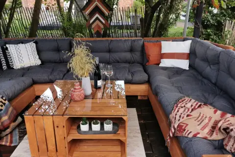 Gemütliche Lounge-Ecke mit einem selbstgebauten Palettensofa. Der Tisch ist ebenfalls aus Holzpaletten gefertigt.