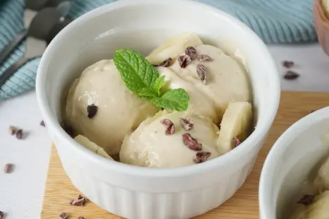 Cremiges Nice Cream Rezept in einer weißen Schale, garniert mit Minze und Kakaonibs. Ein gesunder Genuss!