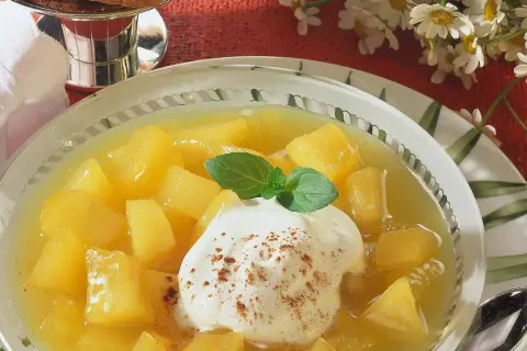 Schüssel mit Apfel-Birnen-Kompott, garniert mit Sahne und Minze. Ein süßer Genuss!