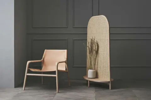 Ein Ledersessel und ein Rattan-Raumteiler mit Trockenblumen – eine stilvolle alternative zu tapete für moderne Räume.
