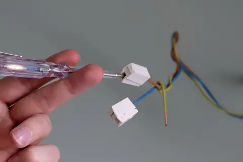 Mit einem Spannungsprüfer wird die Verkabelung für das Anbringen einer Lampe vorbereitet.