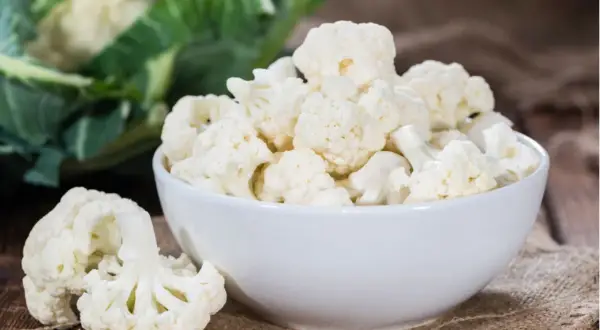 Frischer blumenkohl roh essen ist gesund und lecker. Hier sind Röschen in einer Schüssel und daneben auf einem Holzbrett.