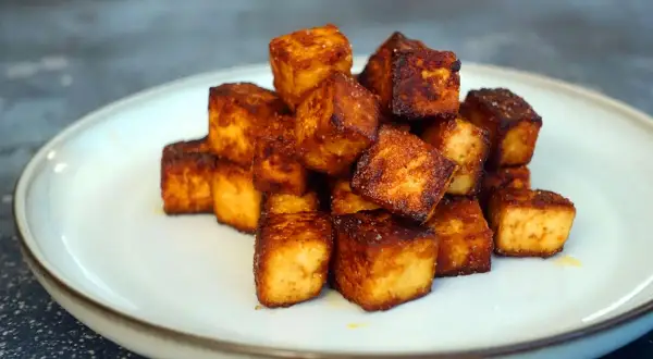 Goldbraun gebratene Tofuwürfel auf einem Teller. Perfekt zum tofu zubereiten für eine knusprige Beilage.