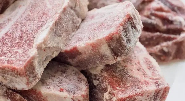 Gefrierbrand essen: Rohes Fleisch, bedeckt mit Eiskristallen, zeigt die Spuren von zu langer Lagerung im Gefrierschrank.