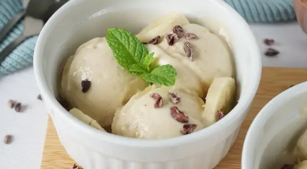 Cremiges Nice Cream Rezept in einer weißen Schale, garniert mit Minze und Kakaonibs. Ein gesunder Genuss!