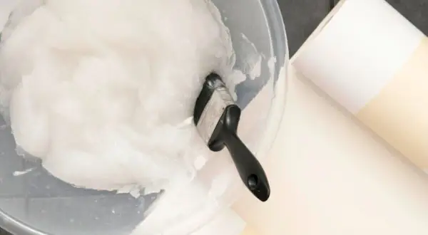 Schüssel mit selbstgemachtem Kleister und Pinsel, dane liegen Tapetenrollen bereit.