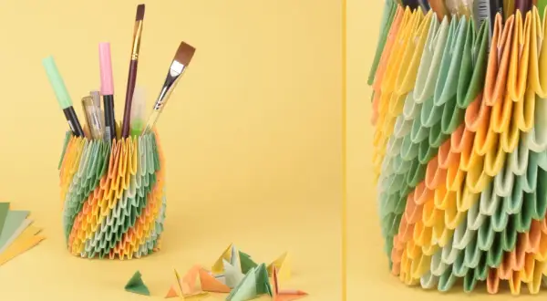 Bunter Stiftehalter aus Origami-Modulen, inspiriert von Papier Ideen. Daneben liegen bunte Papierbögen und kleine Origami-Figuren.