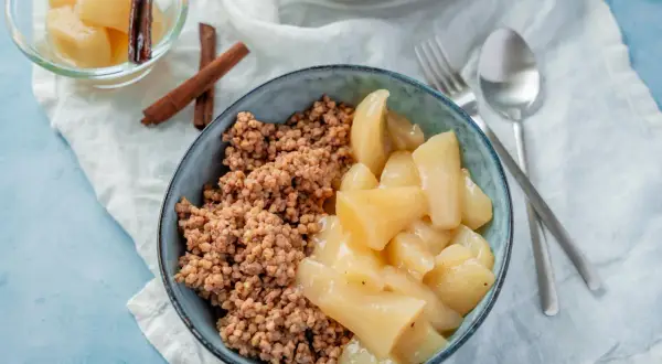 Herzhaftes Buchweizen Porridge mit gedünsteten Apfelstücken und Zimtstangen. Ein köstliches Frühstück.