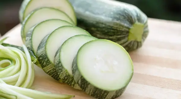 Frische Zucchini, roh essen als Spiralen oder Scheiben auf einem Holzbrett.