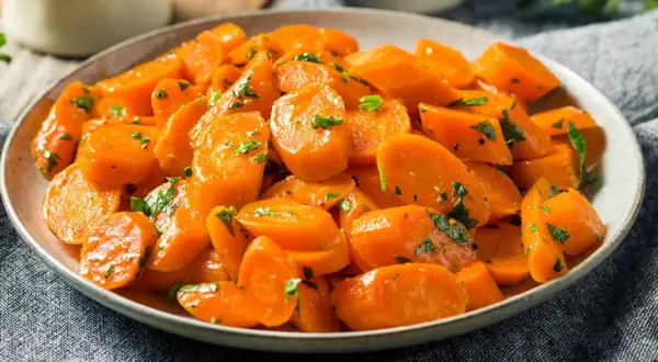 Schüssel mit glasierten, bunte Karotten, garniert mit Petersilie. Ein köstliches Gericht, das Farbe auf den Tisch bringt.