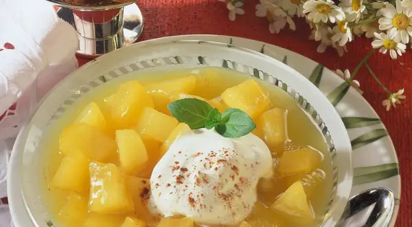 Schüssel mit Apfel-Birnen-Kompott, garniert mit Sahne und Minze. Ein süßer Genuss!