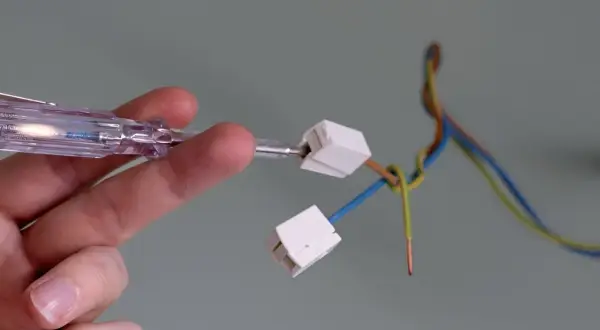 Mit einem Spannungsprüfer wird die Verkabelung für das Anbringen einer Lampe vorbereitet.