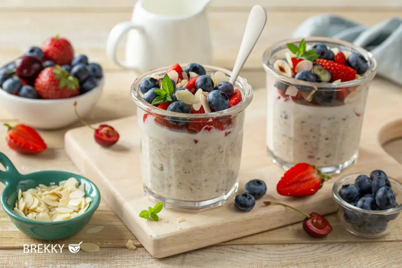 Zwei Gläser mit über Nacht eingeweichten Haferflocken, garniert mit frischen Beeren und Mandelsplittern. Ein gesunder Start in den Tag.