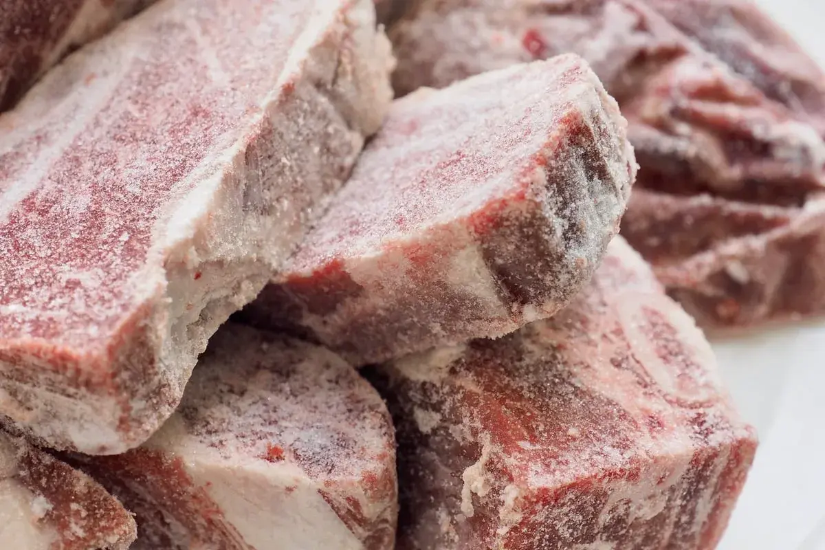 Gefrierbrand essen: Rohes Fleisch, bedeckt mit Eiskristallen, zeigt die Spuren von zu langer Lagerung im Gefrierschrank.