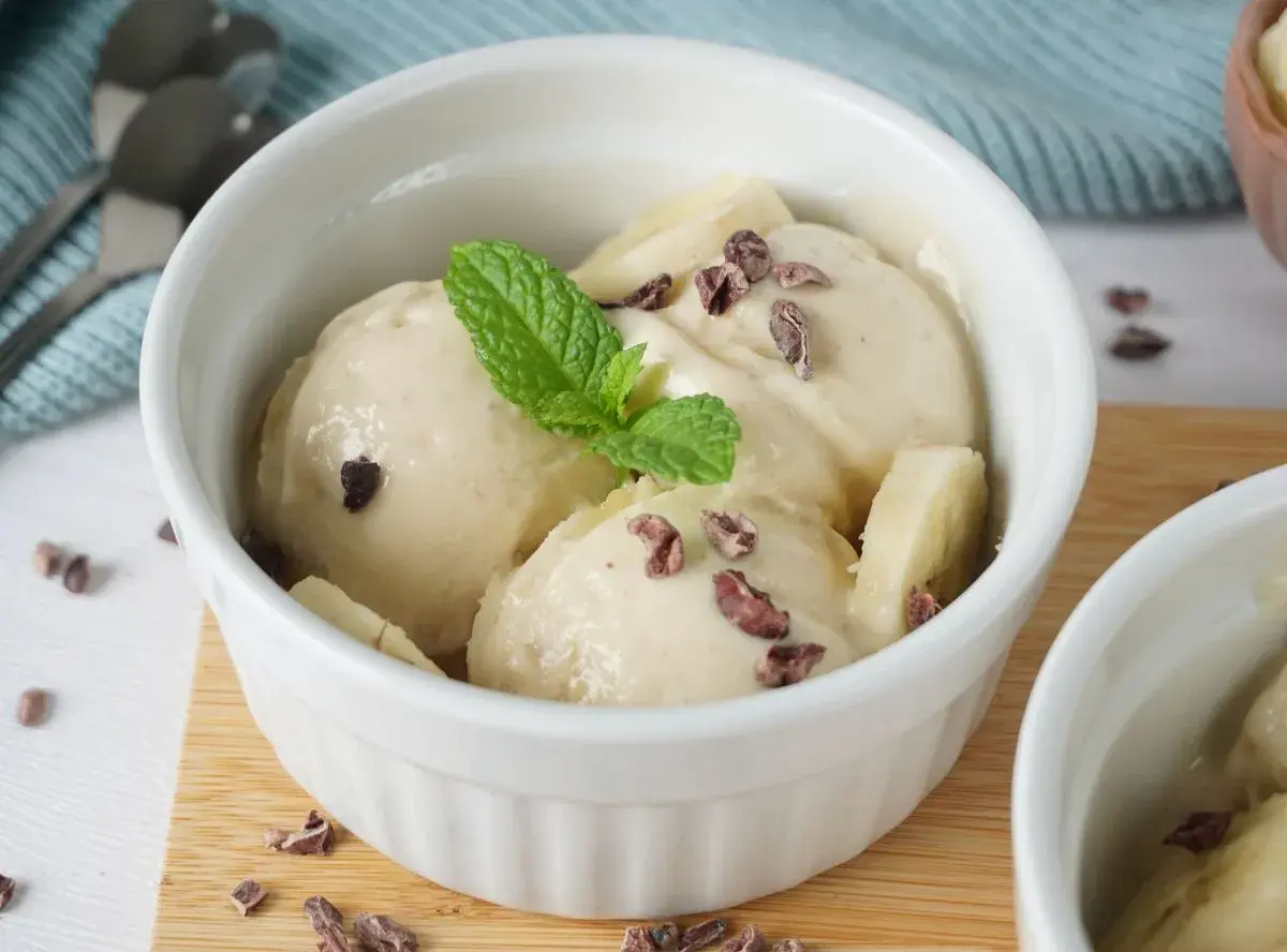 Cremiges Nice Cream Rezept in einer weißen Schale, garniert mit Minze und Kakaonibs. Ein gesunder Genuss!