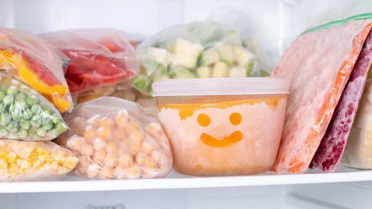 Gefrierbrand vermeiden: Gefrorenes Gemüse und Obst in Beuteln und einem Behälter mit Smiley-Gesicht im Gefrierschrank.