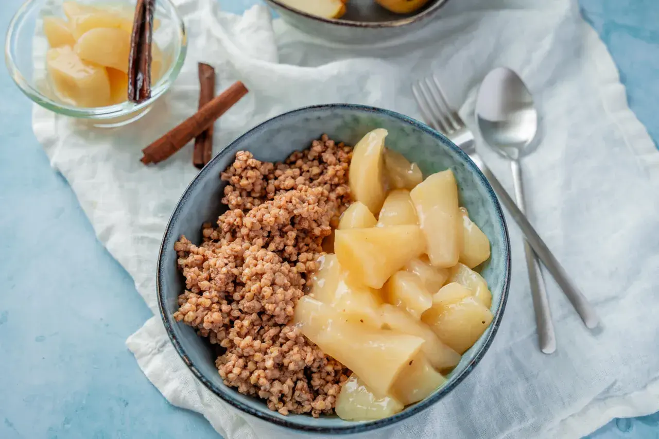 Herzhaftes Buchweizen Porridge mit gedünsteten Apfelstücken und Zimtstangen. Ein köstliches Frühstück.