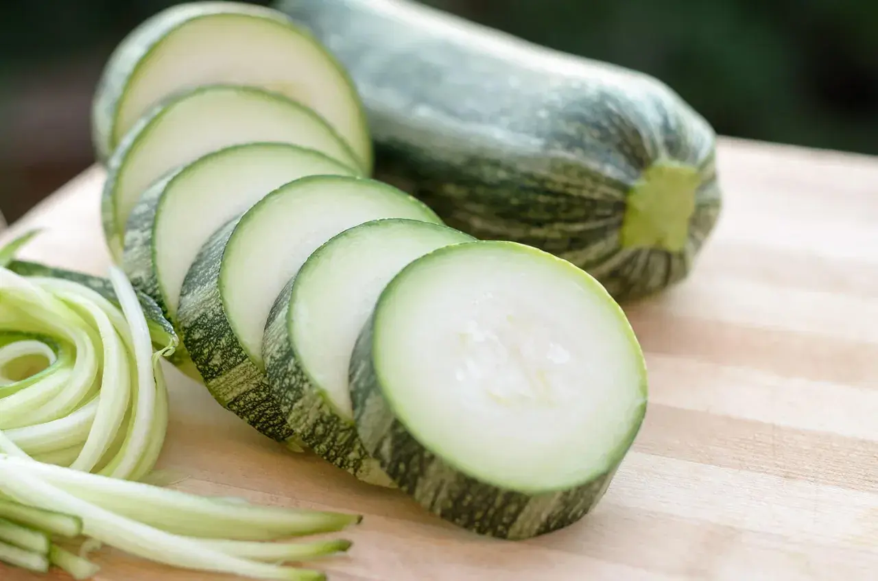Frische Zucchini, roh essen als Spiralen oder Scheiben auf einem Holzbrett.