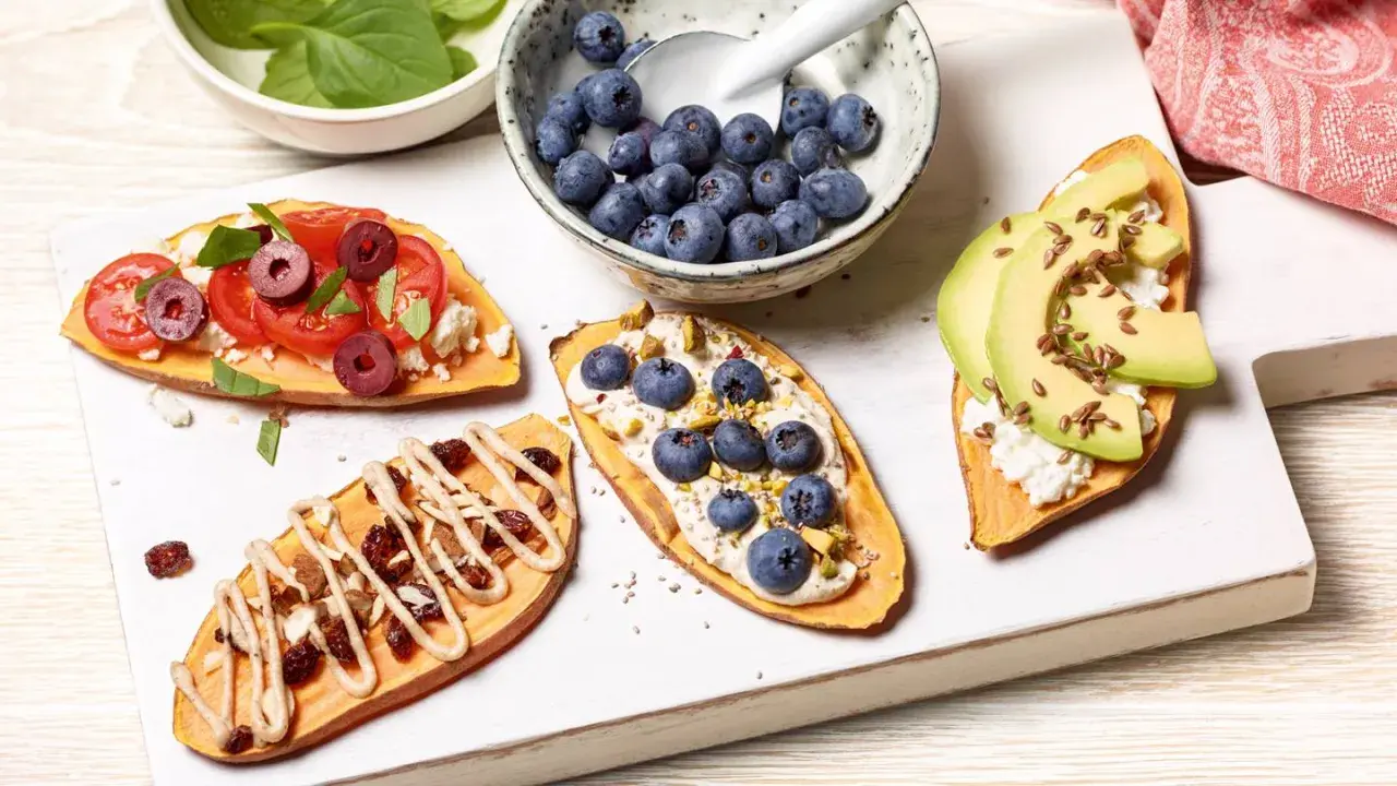 Brotalternativen: Süßkartoffelscheiben belegt mit Tomaten, Feta, Oliven, Blaubeeren, Pistazien, Avocado und Leinsamen.