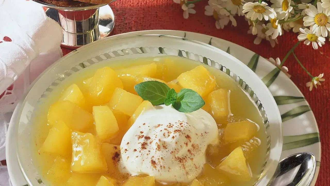 Schüssel mit Apfel-Birnen-Kompott, garniert mit Sahne und Minze. Ein süßer Genuss!