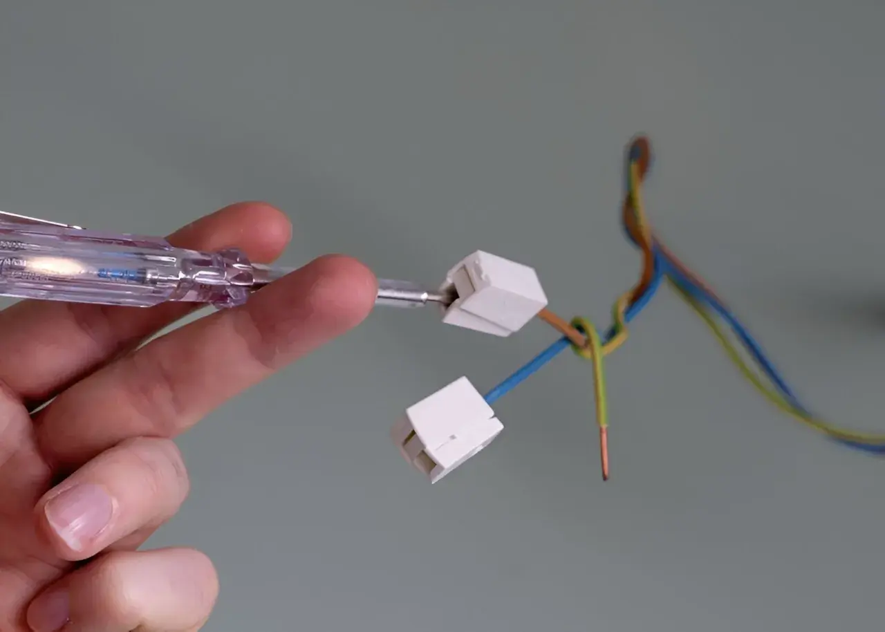 Mit einem Spannungsprüfer wird die Verkabelung für das Anbringen einer Lampe vorbereitet.