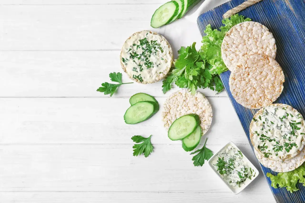 Reiswaffeln mit Frischkäse und Kräutern, Gurkenscheiben und Salat – eine leichte Mahlzeit, die zeigt, welche Reiswaffeln unbedenklich sind.
