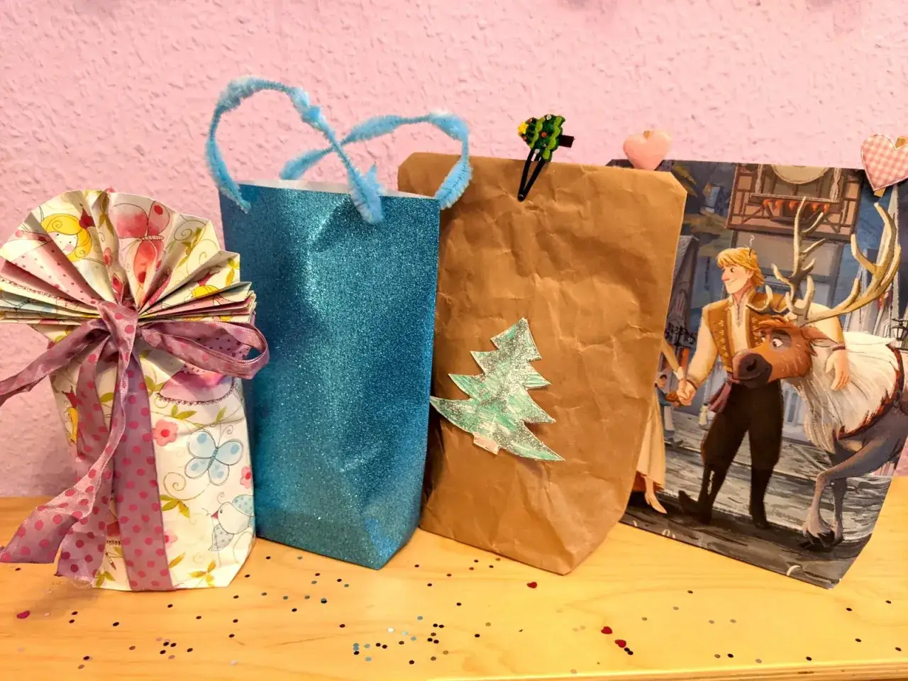Kreative geschenktaschen basteln: bunte Tüten mit Schleifen, Glitzer und Weihnachtsmotiv.
