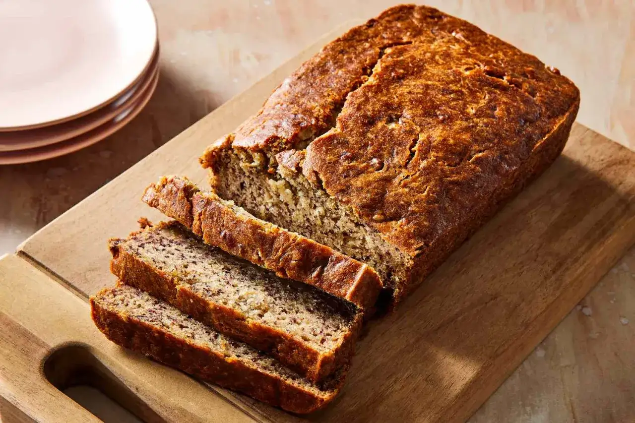 Ein saftiges Bananenbrot ohne Zucker, vegan und k&ouml;stlich, auf einem Holzbrett angeschnitten.