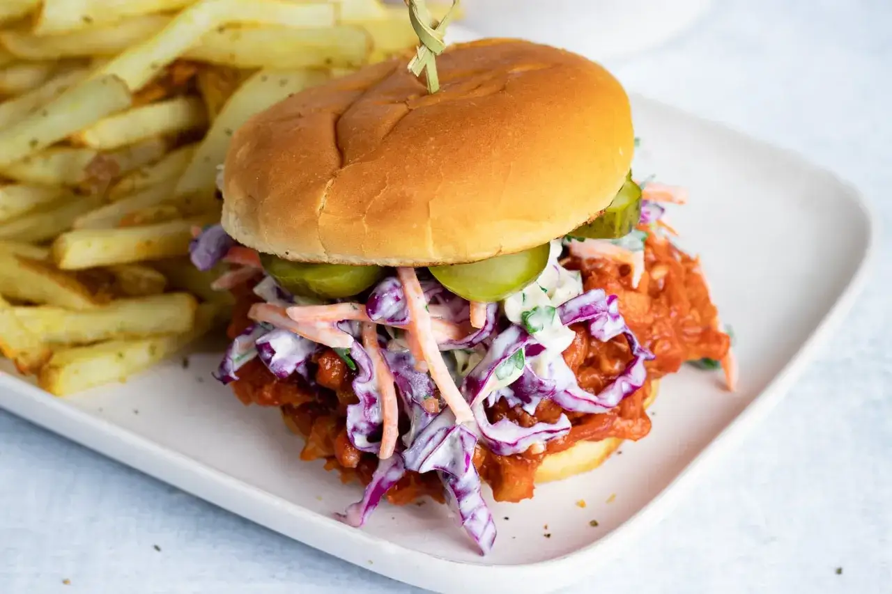Saftiger pulled pork vegetarisch Burger mit Coleslaw und Gurken, dazu knusprige Pommes.