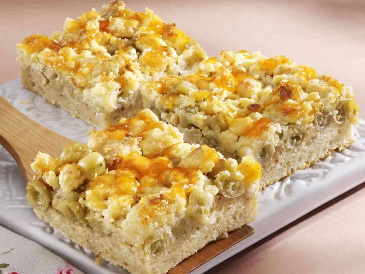Saftiger veganer Stachelbeerkuchen mit Streuseln und glasierten Fr&uuml;chten, serviert auf einem wei&szlig;en Teller.