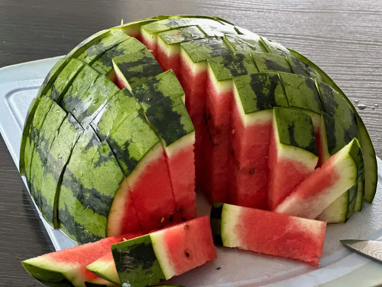 Eine Wassermelone richtig schneiden: So gelingt die perfekte Pr&auml;sentation. Saftige rote St&uuml;cke auf einem Brett.