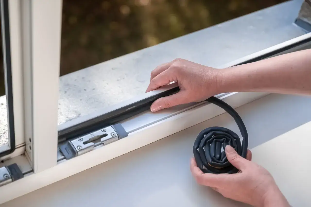 H&auml;nde legen eine neue Fensterdichtung an. So einfach l&auml;sst sich die Dichtung am Fenster erneuern und Zugluft vermeiden.